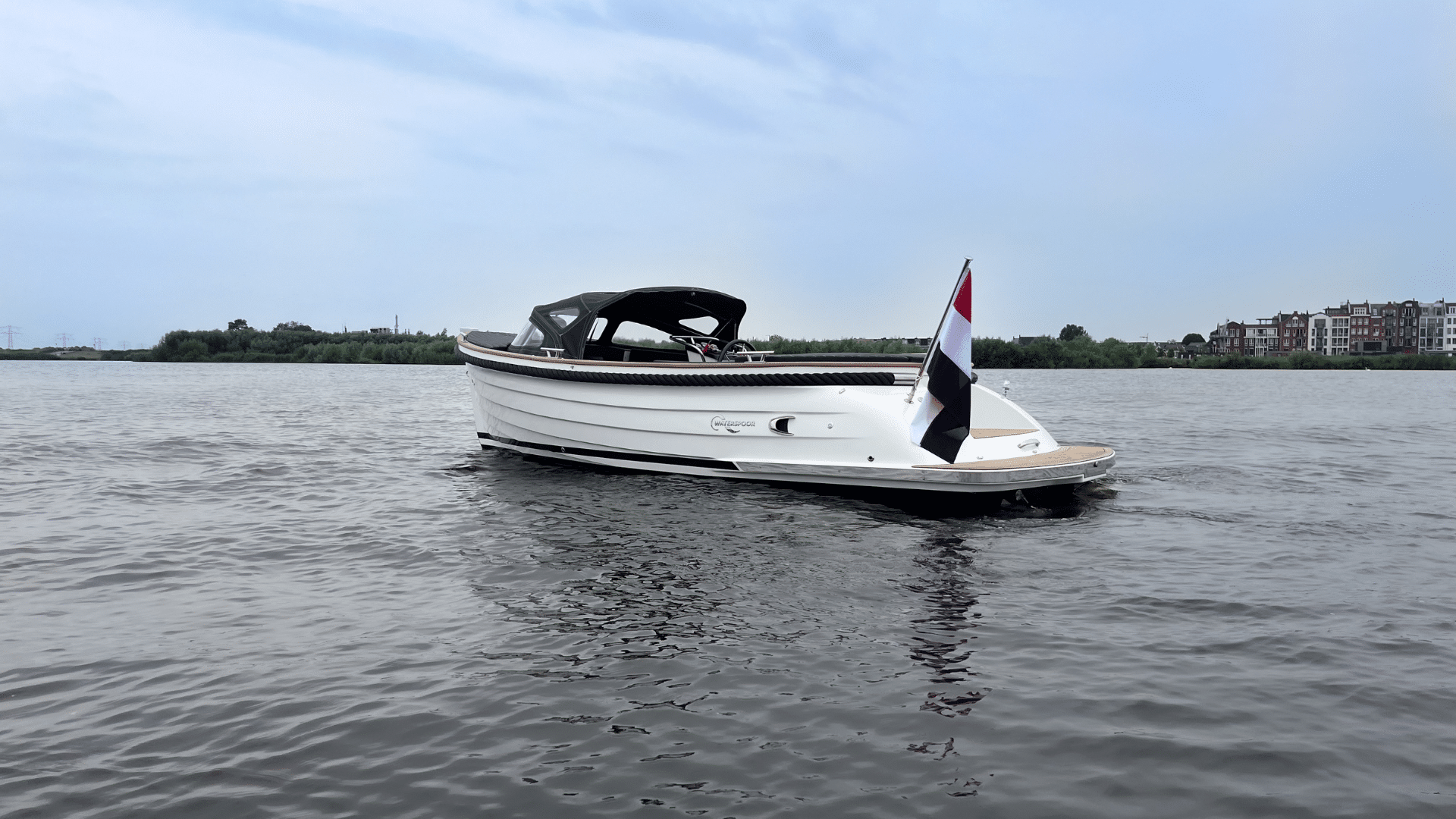 Vaartlander_Waterspoor-646-Outboard-2 Zijaanzicht van de Waterspoor 646 Outboard met zwarte kap en Nederlandse vlag.