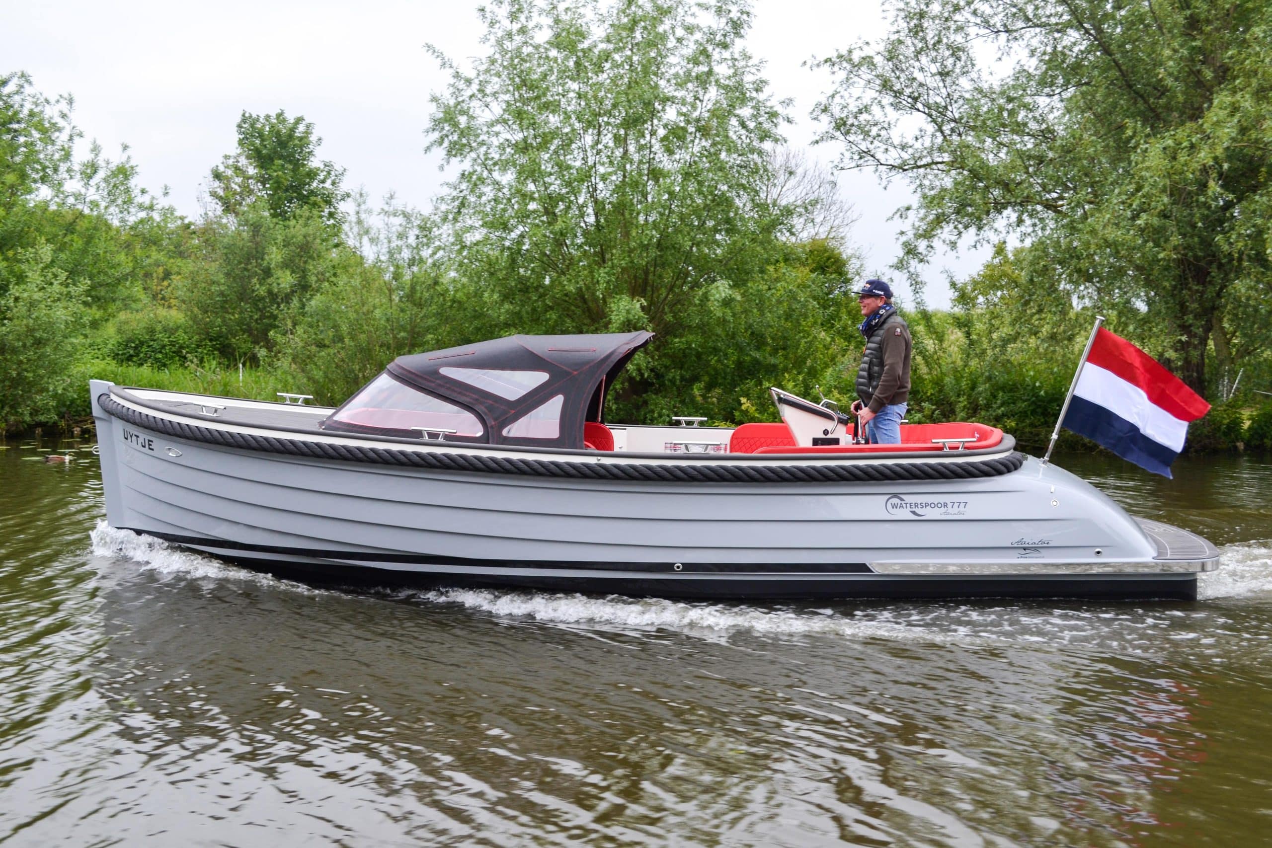 Vaartlander_Waterspoor-777-Aviator-4 Waterspoor 777 Aviator met kap omhoog, varend langs groene oever.